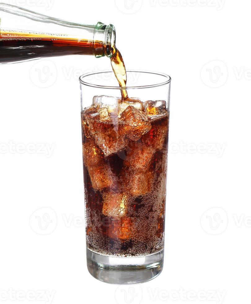 fles coke gieten in drank glas met ijsblokjes geïsoleerd foto