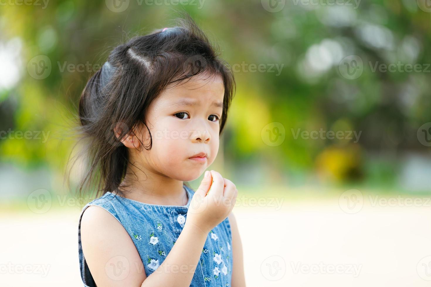 portret Aziatische kind meisje snack eten in de buitenlucht. kind hongerig na het spelen in het openbare park. kinderen hebben het warm en zweten op haar gezicht vanwege het warme weer. baby van 5 jaar oud. lege ruimte foto