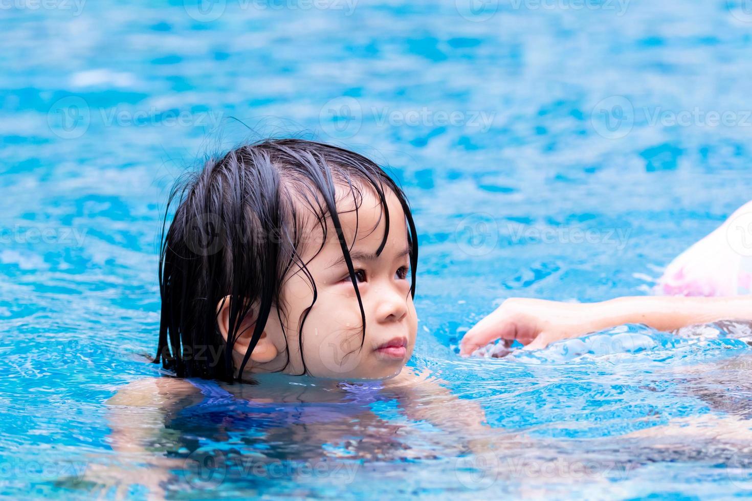 portret schattig Aziatisch kind meisje spelen in helderblauw zwembad. kinderen vinden het leuk om in het water te sporten. kind van 4 jaar is nat. foto