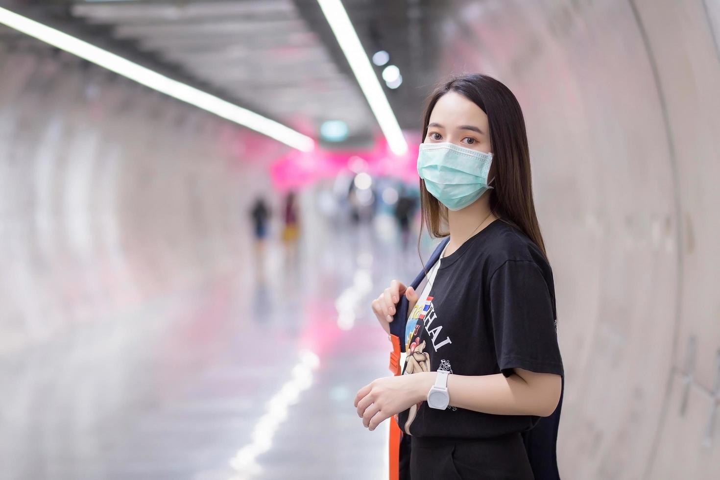 Aziatische mooie vrouw draagt een zwart shirt en een medisch gezichtsmasker terwijl ze de metrotunnel binnenloopt. gezondheidszorg, vervuiling pm2.5 en nieuw normaal concept. foto