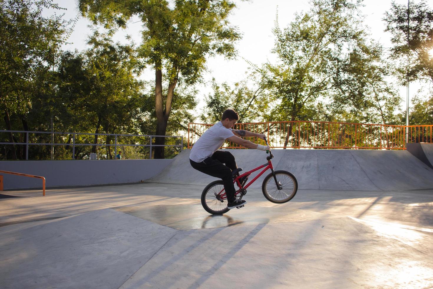 bmx-rijderstraining en trucs doen op straatplein, fietsstuntrijder in cocncrete skatepark foto