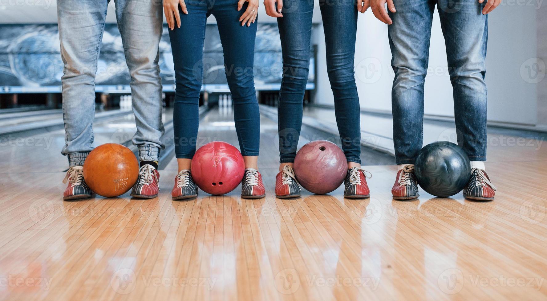 ballen bij de benen vasthouden. bijgesneden weergave van mensen bij de bowlingclub die klaar zijn om plezier te hebben foto