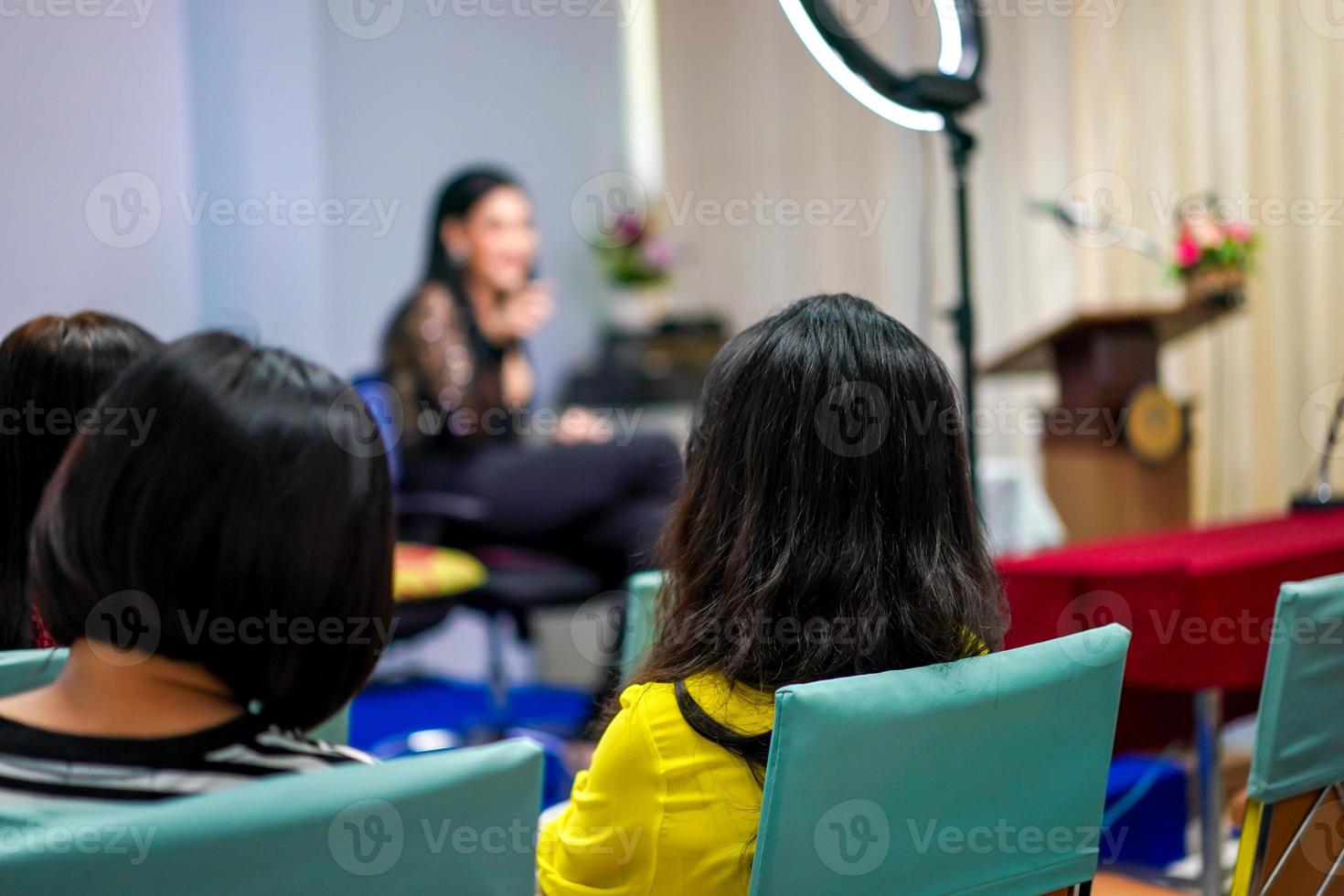 publiek en deelnemer luisteren naar leraar en docent vooraan op het podium over gezichtsmake-up voor vrouwen. foto