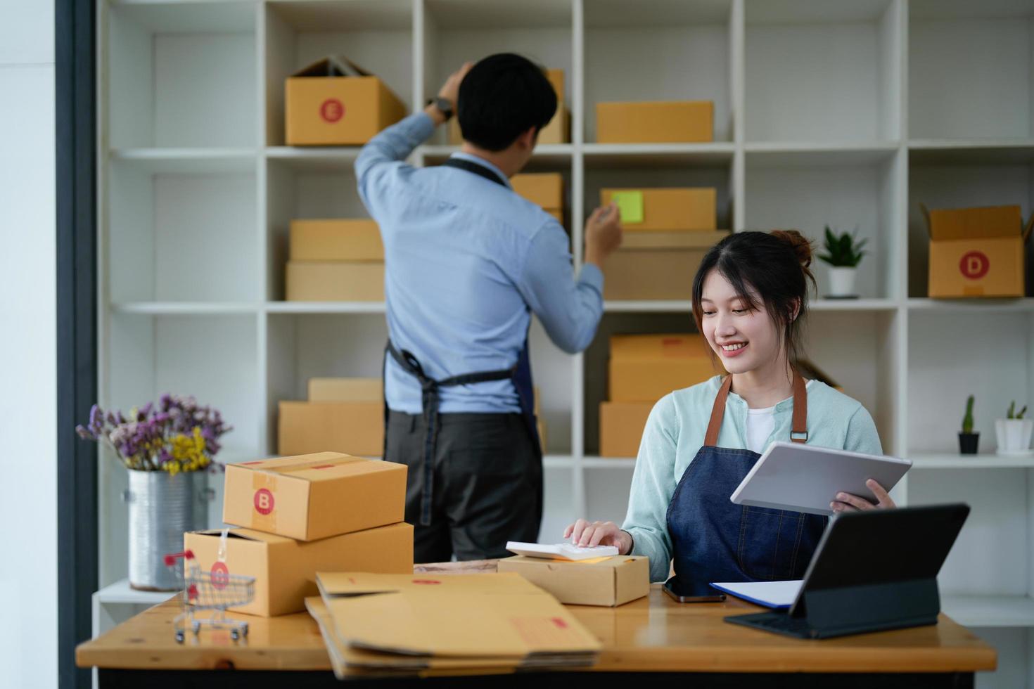 startende eigenaar van een klein bedrijf werken met tablet op de werkplek. freelance man en vrouw verkoper controleren productbestelling, verpakken van goederen voor levering aan klant. online verkoop, e-commerce, verzendconcept foto