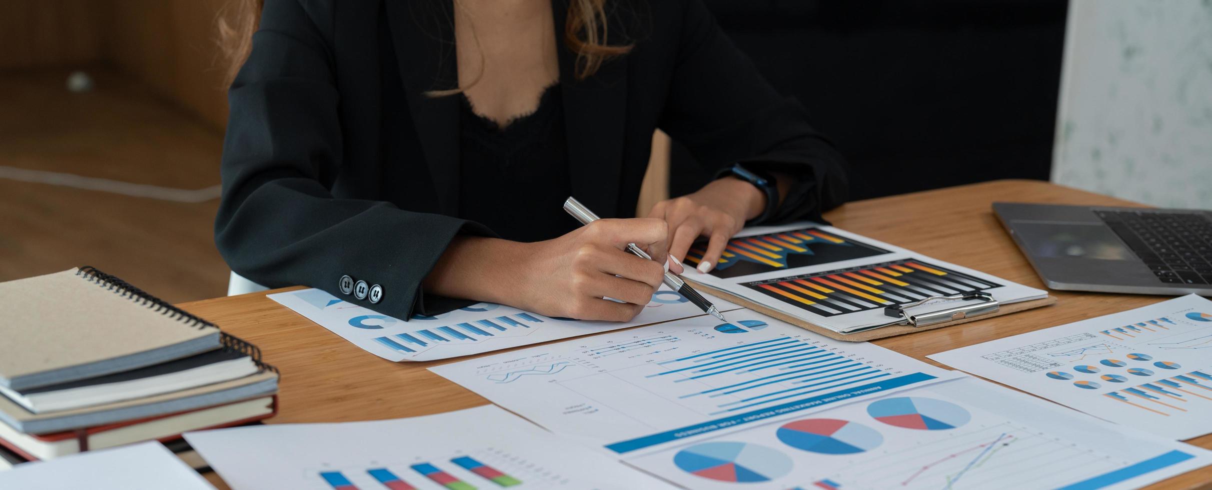 jonge zakenvrouw die rekenmachine en laptop gebruikt om wiskunde te financieren op houten bureau, belasting, boekhouding, statistiek en analytisch onderzoeksconcept foto