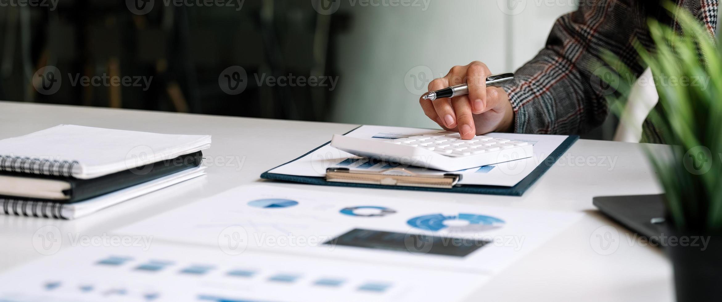 close-up zakenvrouw met behulp van rekenmachine voor do math finance op houten bureau in kantoor en zakelijke achtergrond, belasting, boekhouding, statistiek en analytisch onderzoeksconcept foto