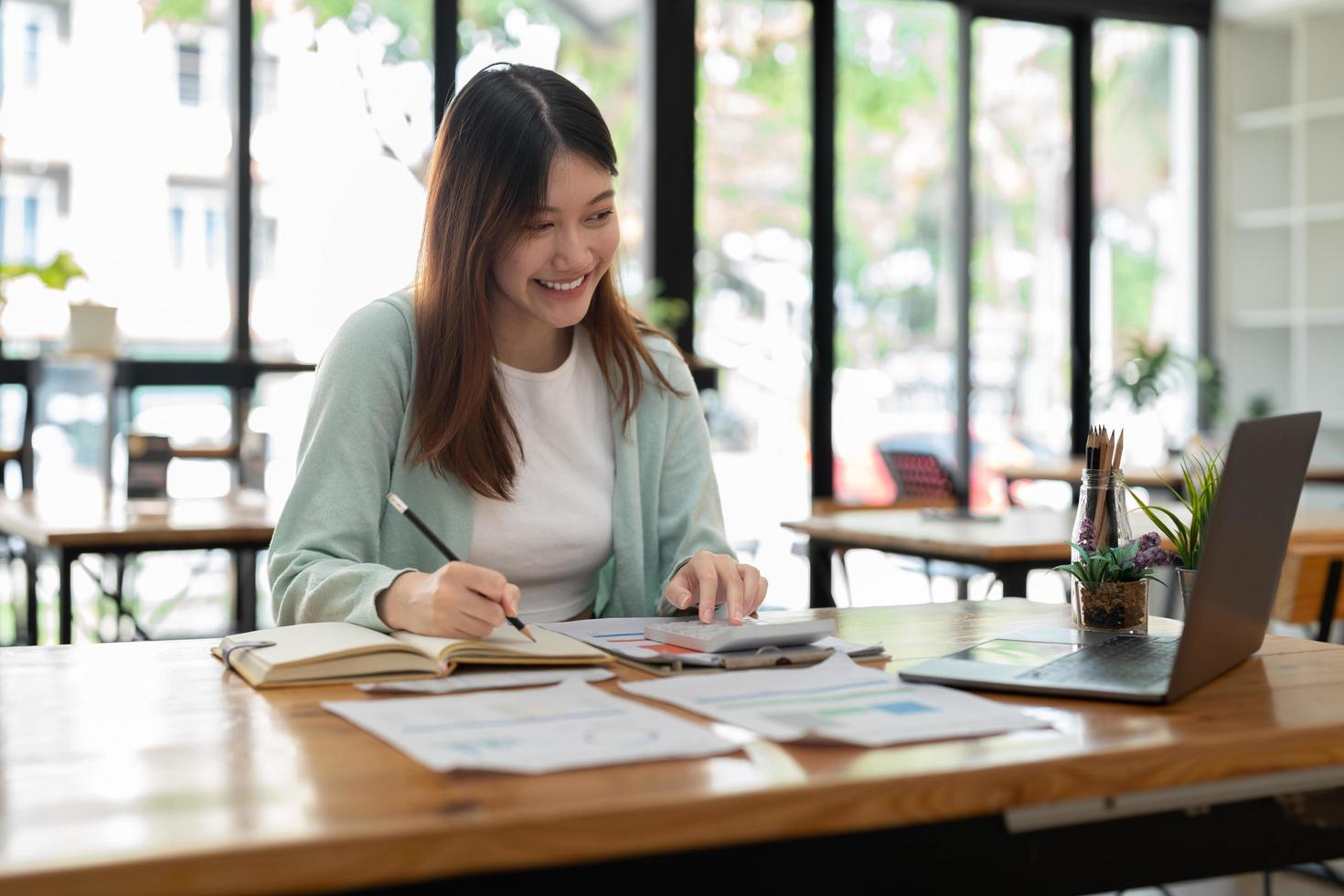 zakelijke accountant vrouw met behulp van rekenmachine voor do math finance op houten bureau in kantoor en zakelijke achtergrond, belasting, boekhouding, statistiek en analytisch onderzoeksconcept foto