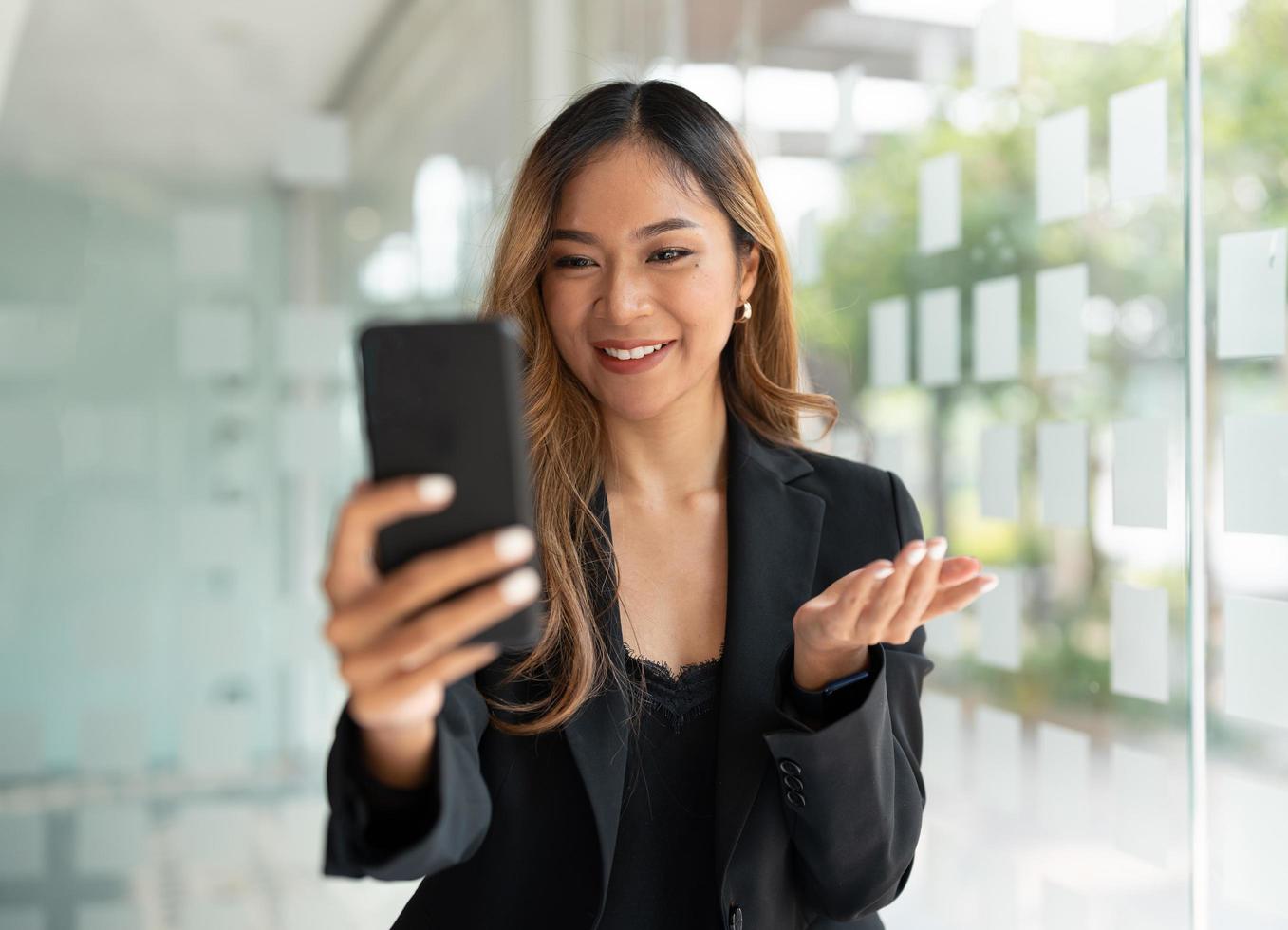 aziatische zakenvrouw zwaaiende vuisten, kreeg goed nieuws op mobiele smartphone op kantoor, social media netwerk, videobellen, communicatie. foto