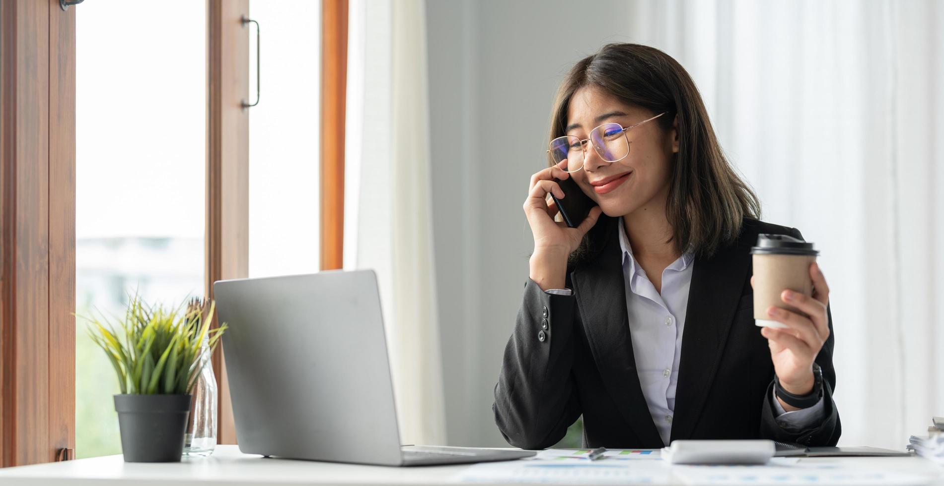 jonge accountant met smartphone om marketingadviseurs te bellen en laptopcomputer te gebruiken om de verkoopgroei op de wereldwijde werkplekmarkt te analyseren. boekhoudconcept foto