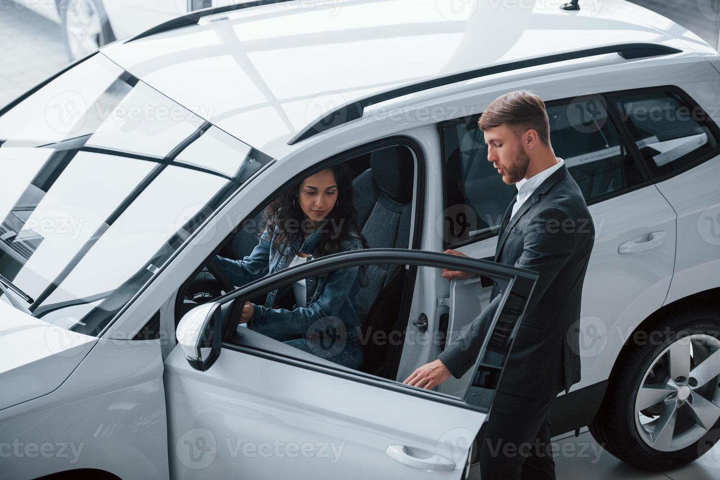 je zult je op je gemak voelen. vrouwelijke klant en moderne stijlvolle bebaarde zakenman in de autosalon foto