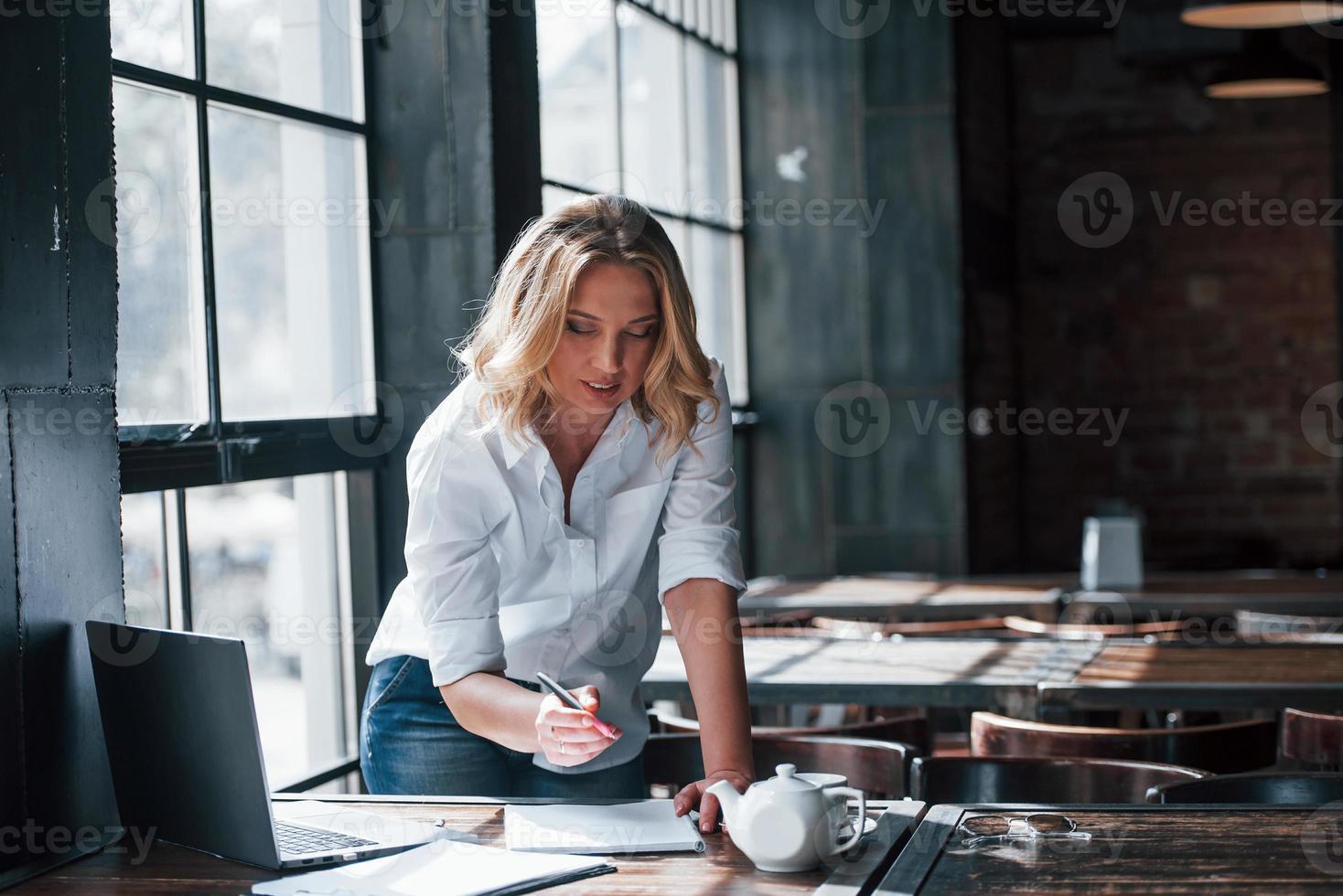 werk goed gedaan. zakenvrouw met krullend blond haar binnenshuis in café overdag foto