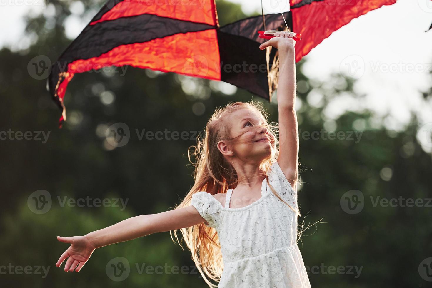 goede wind. gelukkig meisje in witte kleren veel plezier met vlieger in het veld. prachtige natuur foto
