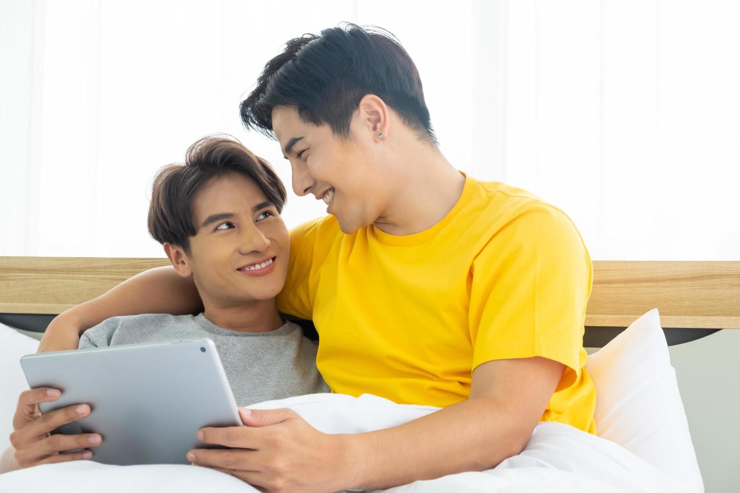 Aziatische homo homoseksueel paar knuffelen en omarmen op het bed. gendergelijkheid en juist concept, speels en romantisch moment. foto
