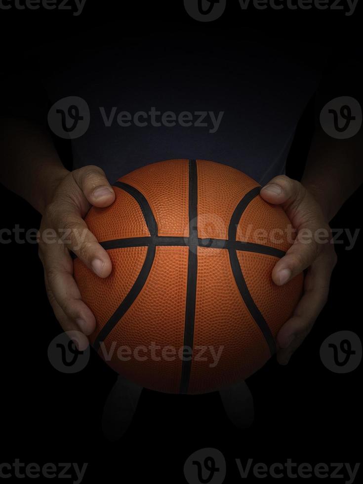 basketbalspeler die een bal houdt tegen zwarte achtergrond foto