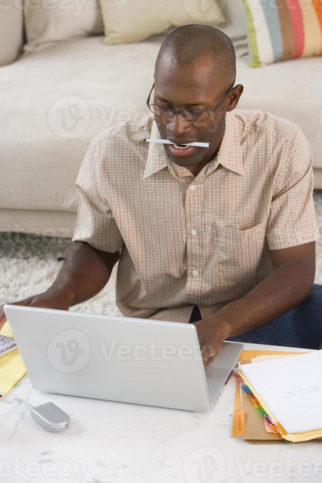 man met pen in mond op laptopcomputer, verhoogde weergave foto