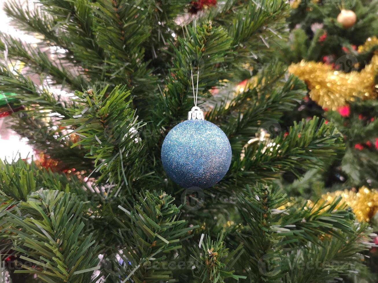 versierde groene kerstboomversieringen hebben een blauwe bal, gouden bladeren op een wazige achtergrond foto