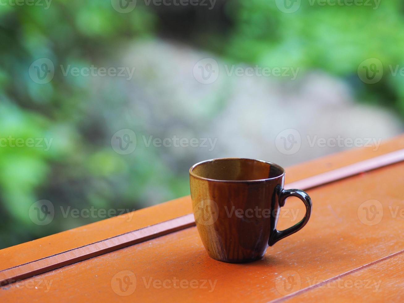 bruin koffiekopje op de houten tafel bokeh met de natuur wazig van achtergrond foto