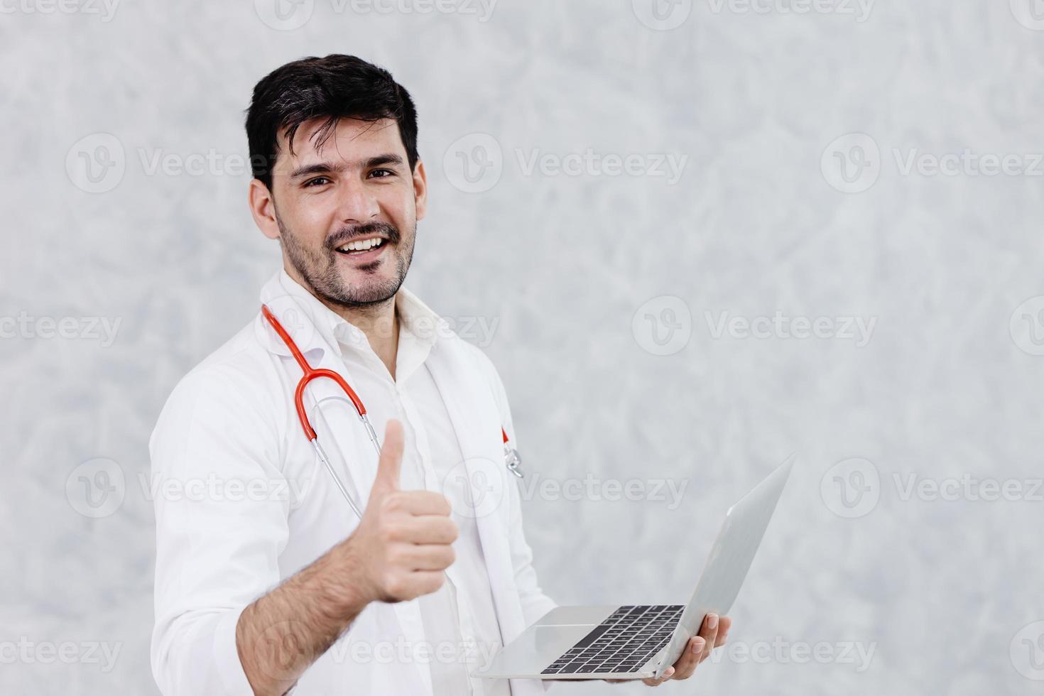 gelukkige dokter knappe man duimschroef opwaarts goed werk met computer laptop. foto