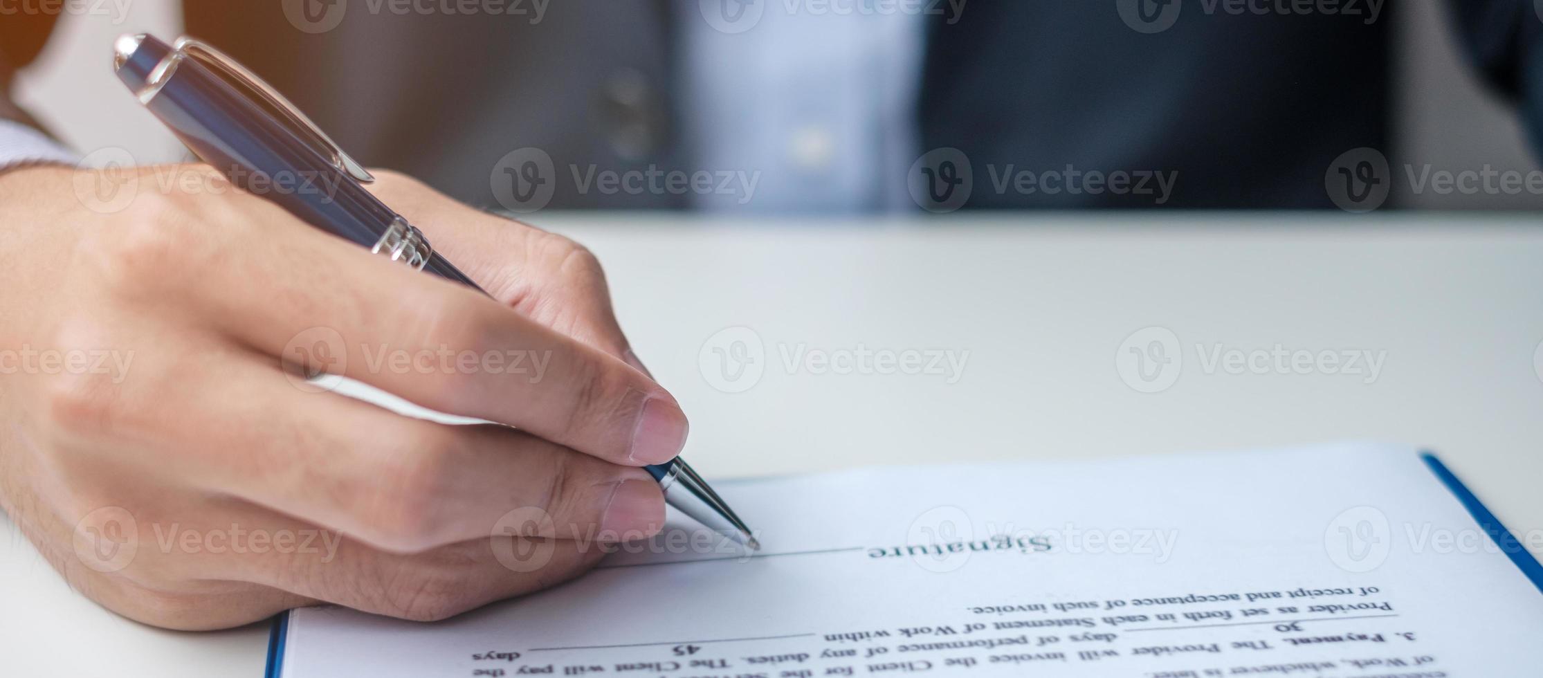 man ondertekent contractdocumenten na het lezen, man houdt pen vast en keurt bedrijfsrapport goed. contractovereenkomst, wet en dealconcepten foto