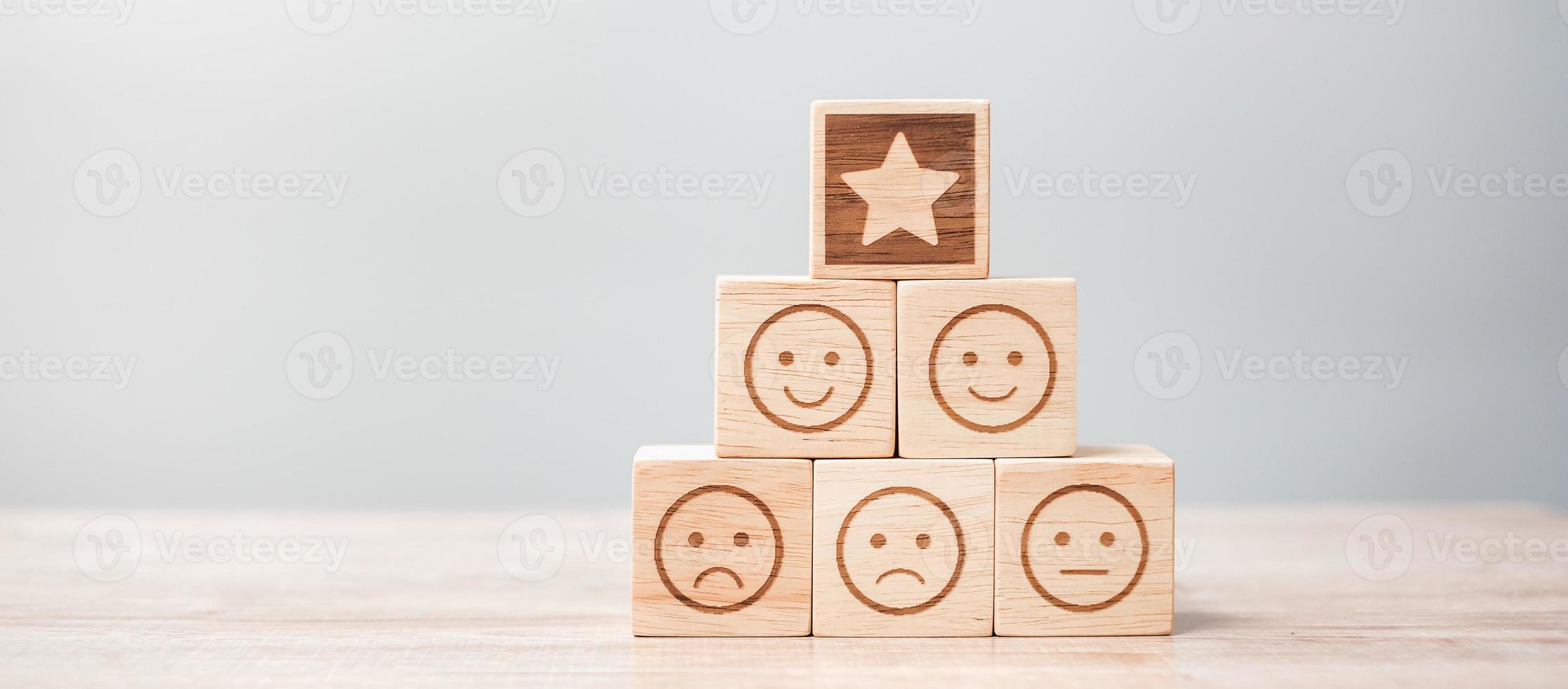 emotie gezicht en ster symbool blokken op tafel achtergrond. servicebeoordeling, rangschikking, klantbeoordeling, tevredenheid, evaluatie en feedbackconcept foto