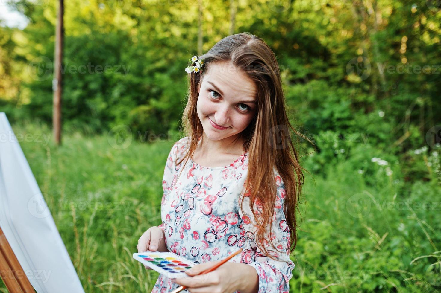 portret van een aantrekkelijke jonge vrouw in lange jurk schilderen met waterverf in de natuur. foto