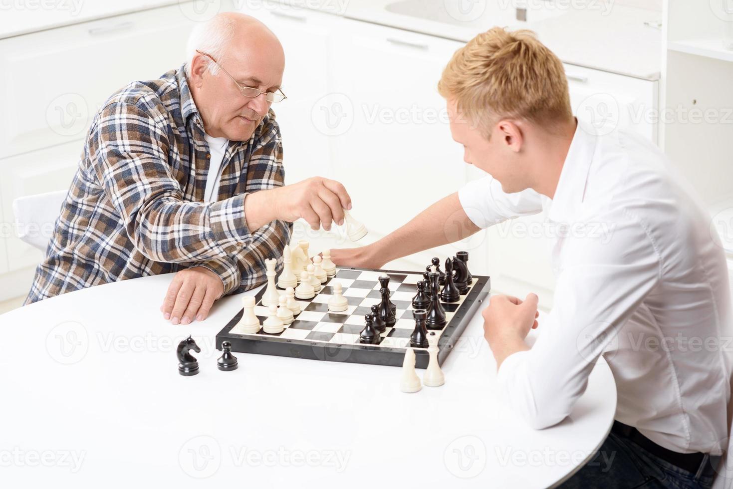kleinzoon en grootvader schaken in de keuken foto