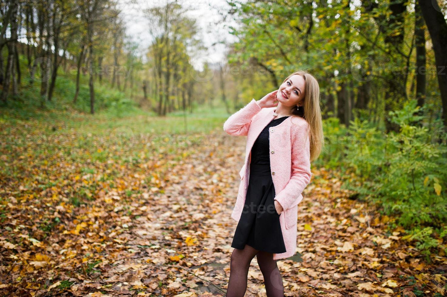 jong blond meisje met roze jas gesteld op herfst park. foto