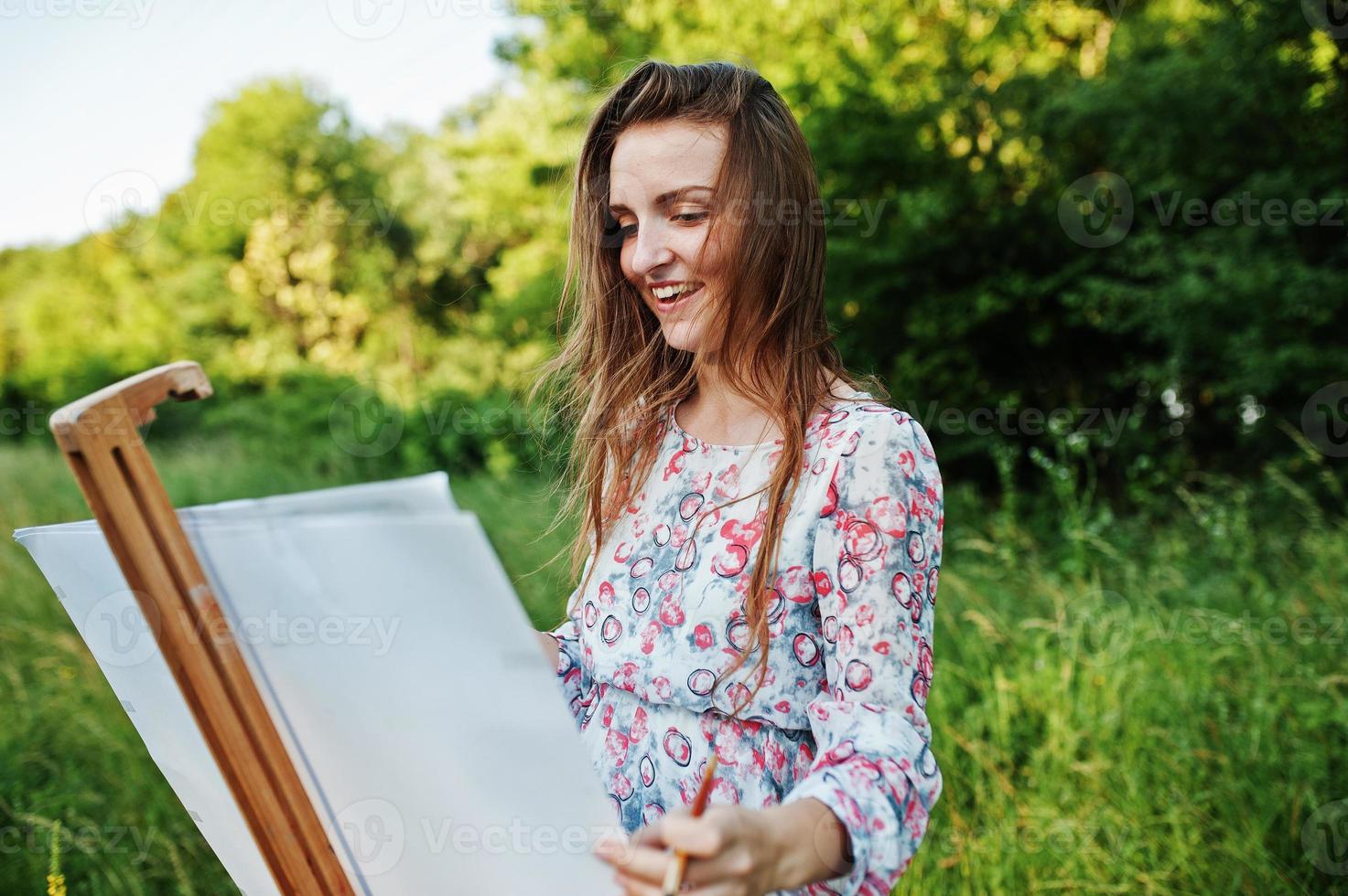 portret van een aantrekkelijke jonge vrouw in lange jurk schilderen met waterverf in de natuur. foto