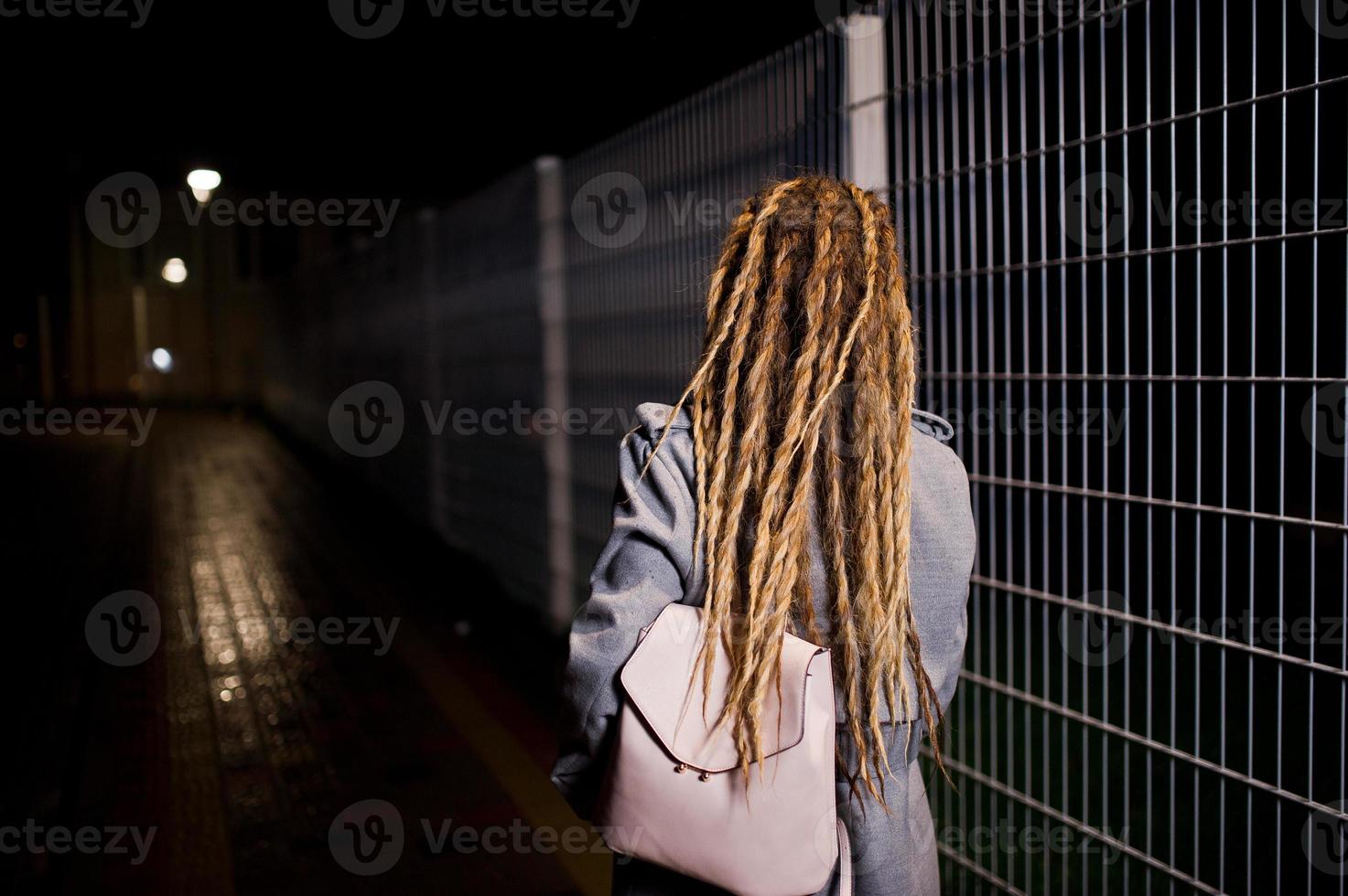 meisje met dreadlocks lopen 's nachts straat van de stad. foto