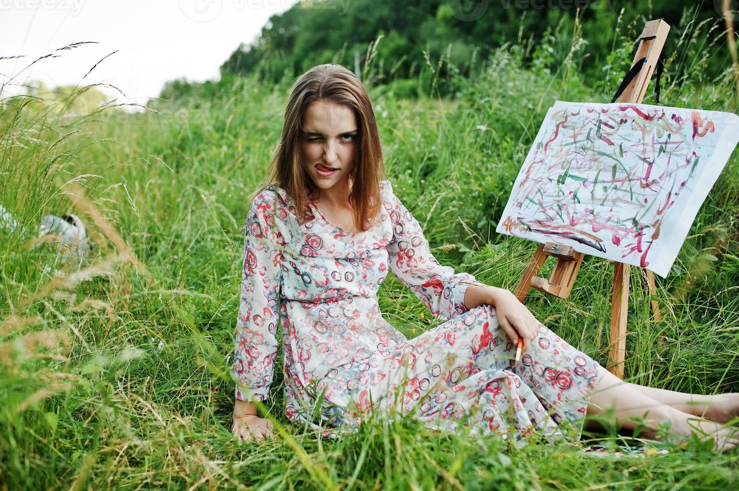 portret van een grappig meisje dat rare gezichtsuitdrukkingen maakt tijdens het schilderen op de weide. foto