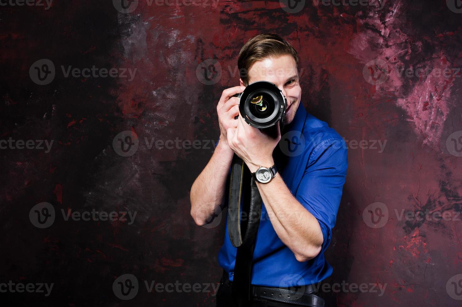 studioportret van stijlvolle professionele fotograaf man met camera, draag op blauw shirt en stropdas. foto