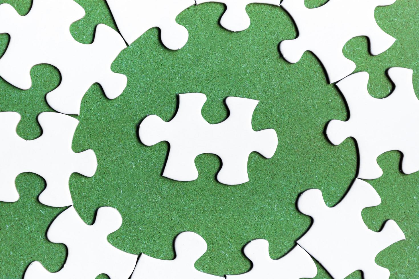witte puzzel met enkele ontbrekende stukjes op groene achtergrond. plat liggen. foto