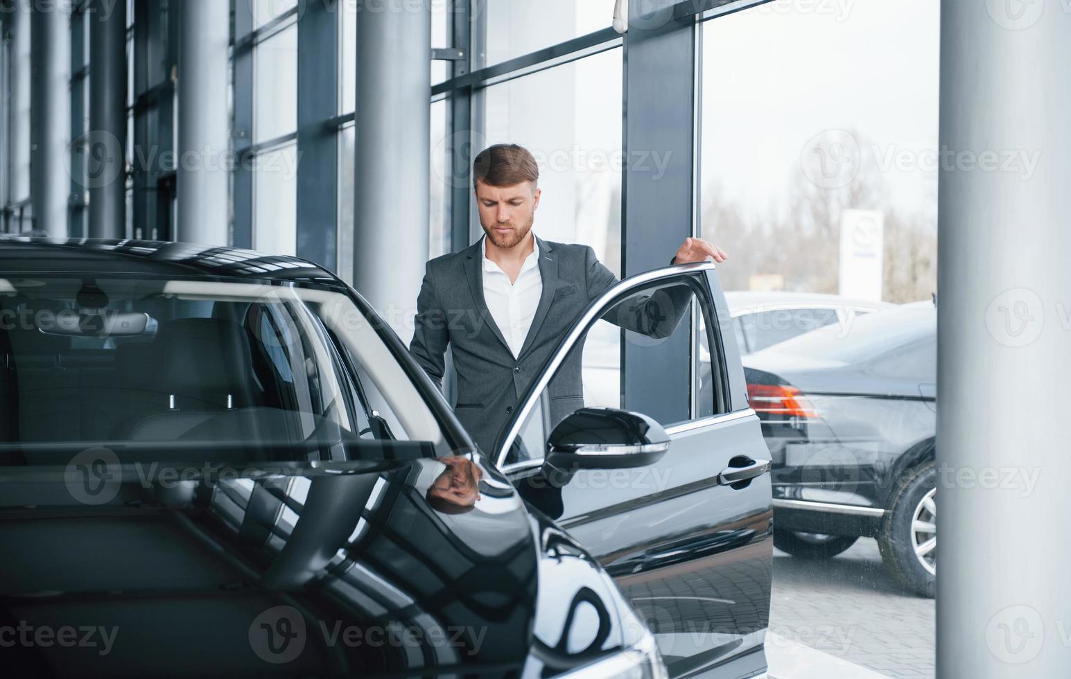 laten we naar de baan gaan. moderne stijlvolle bebaarde zakenman in de autosalon foto