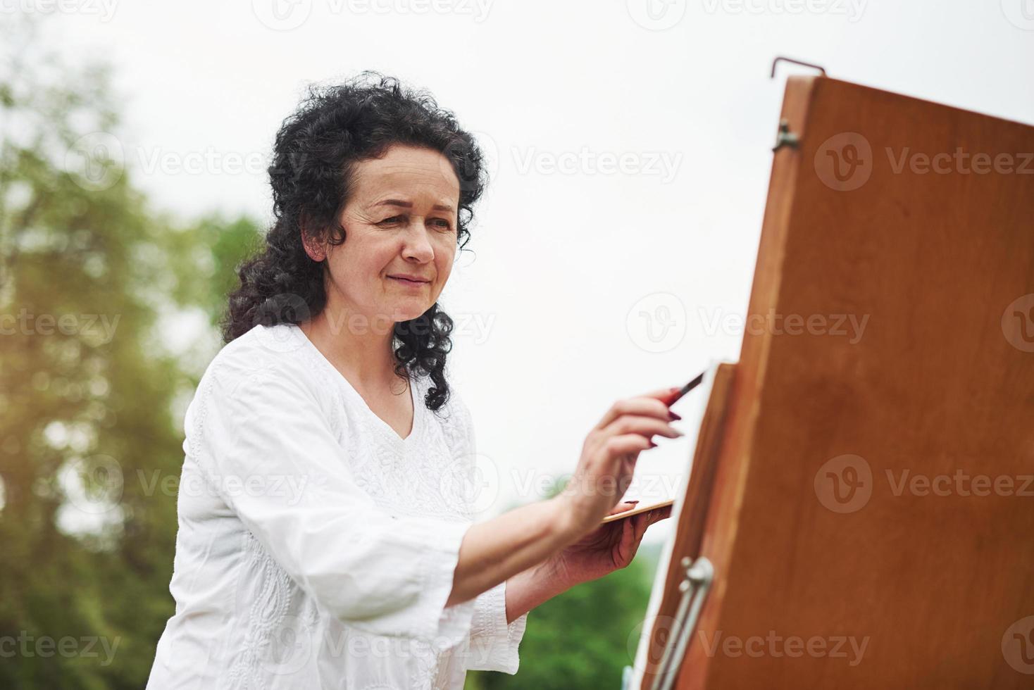 mooi zonlicht. portret van volwassen schilder met zwart krullend haar in het park buiten foto