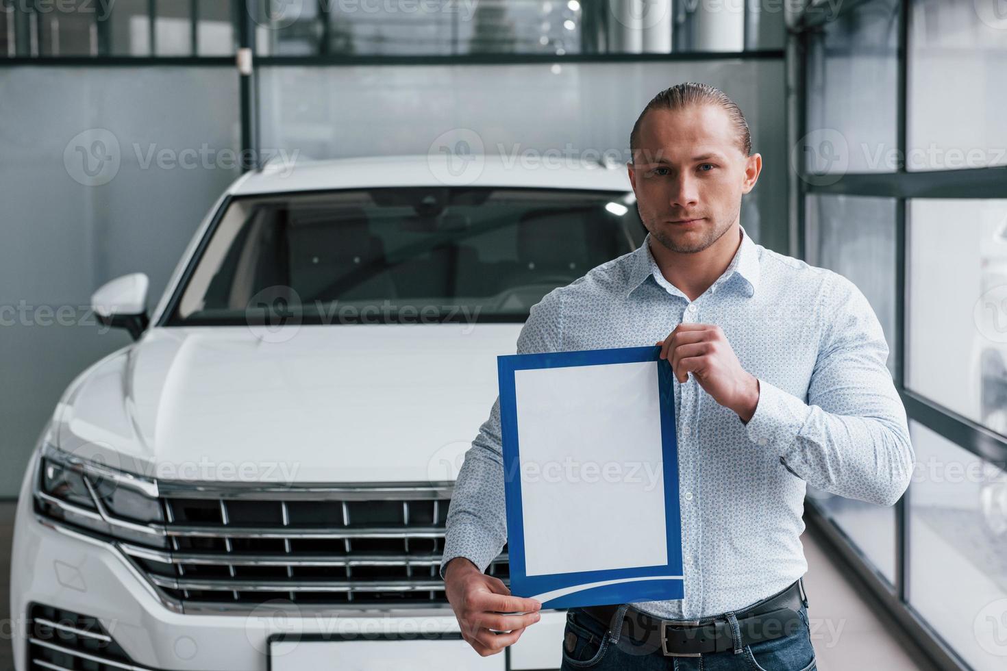 Manager staat voor moderne witte auto met papier en documenten in handen foto