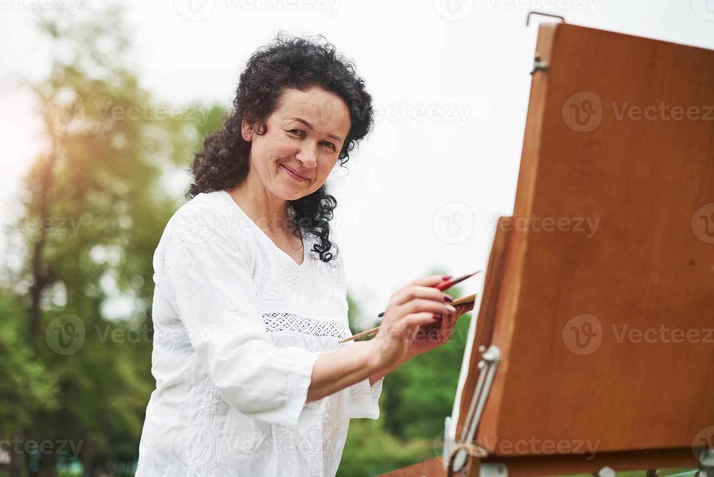 goede atmosfeer. portret van volwassen schilder met zwart krullend haar in het park buiten foto