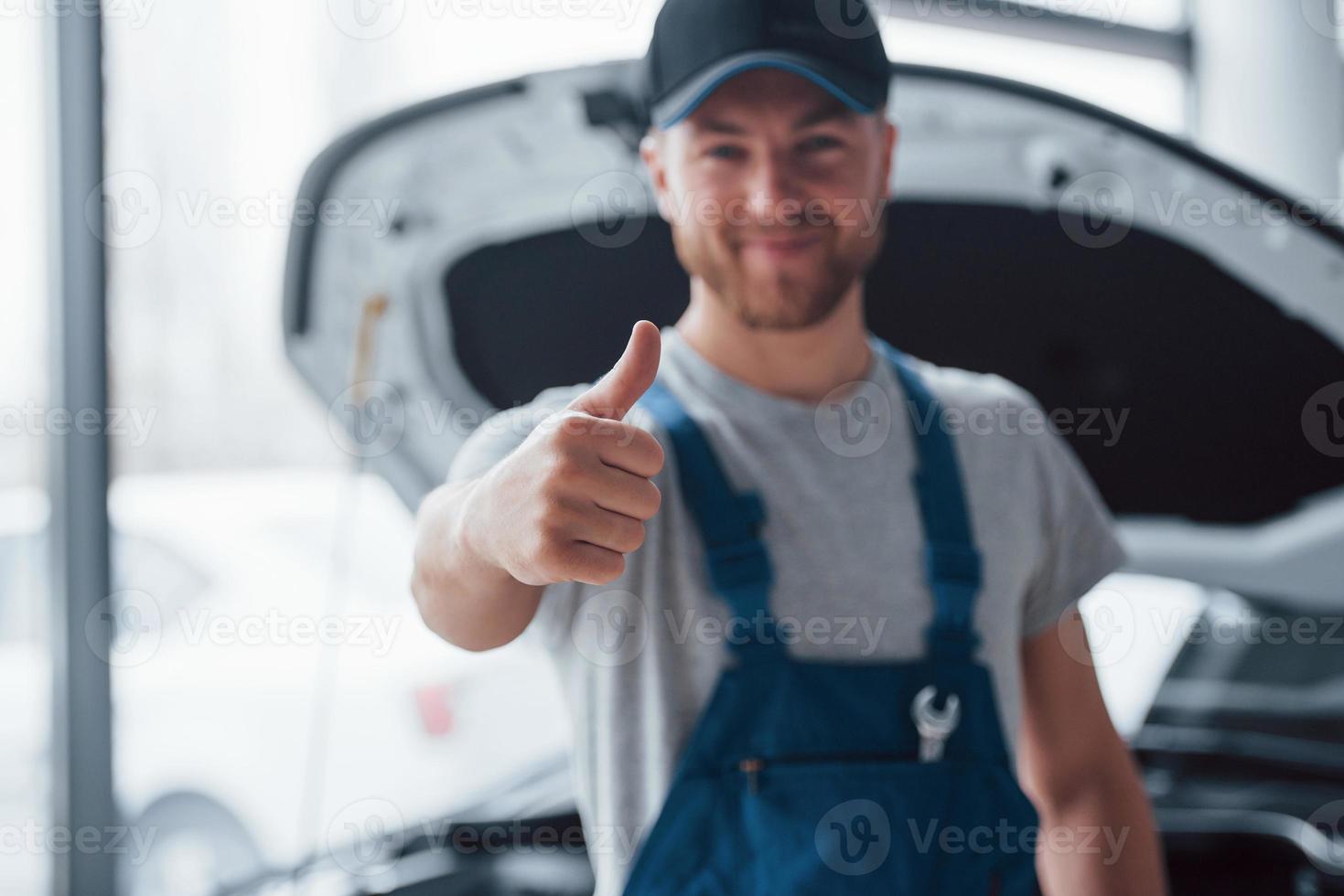 werk goed gedaan. werknemer in het blauw gekleurde uniform staat in de autosalon foto