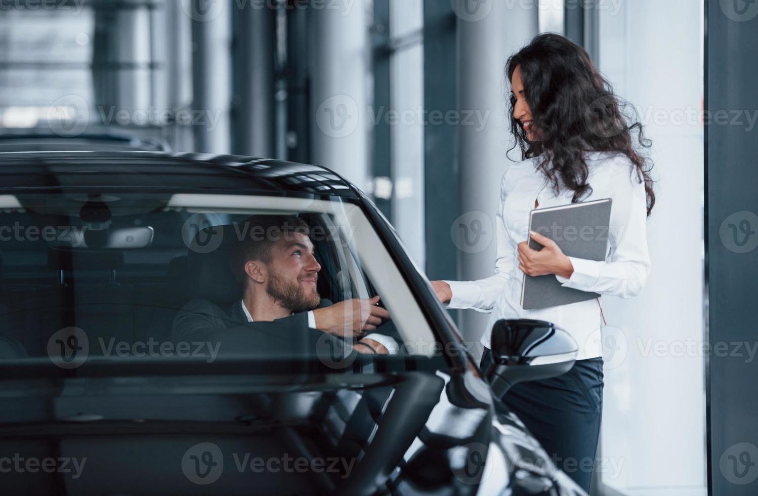 hier zijn je sleutels. mannelijke klant en moderne zakenvrouw in de autosalon foto