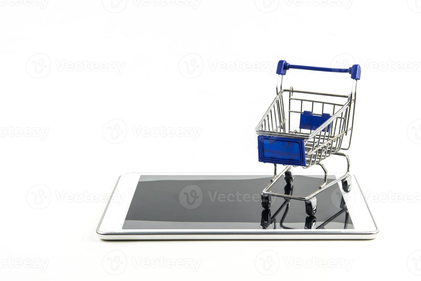 winkelwagentje met tablet op witte backgrond, betekent online winkelen foto