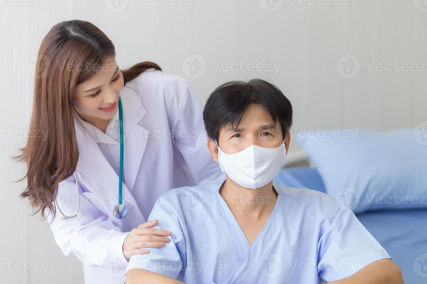 aziatische doktersvrouw die praat met een man-patiënt die een gezichtsmasker draagt over zijn gezondheidssymptoom terwijl hij in een rolstoel in het ziekenhuis zit. foto