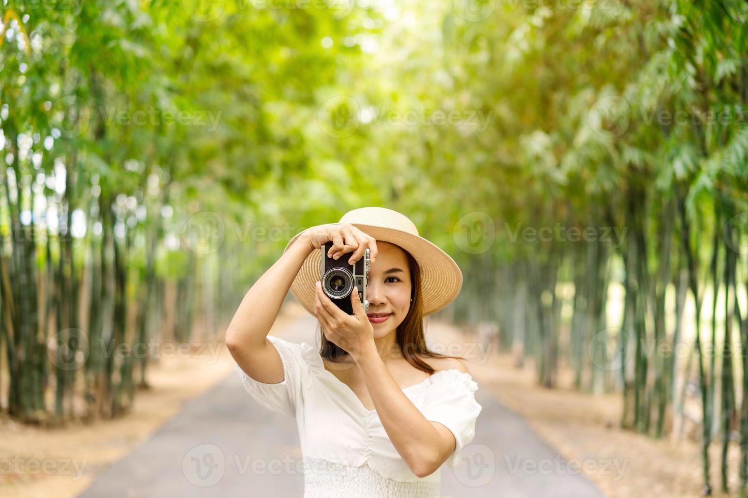 jonge gelukkige vrouw die geniet van en een foto maakt in het bamboebos tijdens het reizen in de zomer