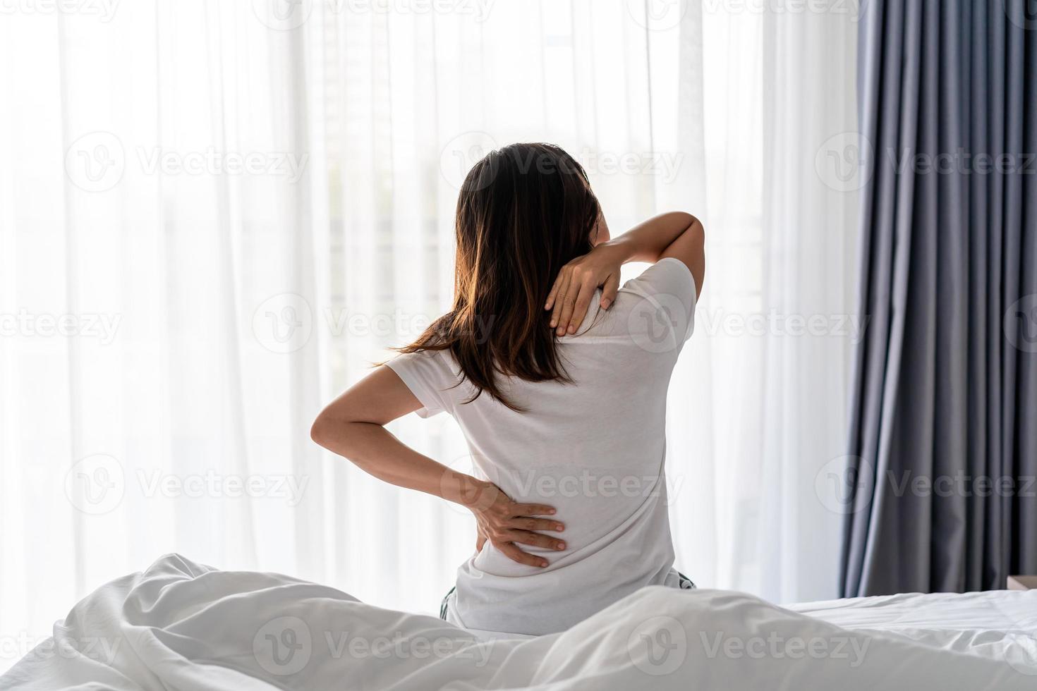 vrouw die lijdt aan rugpijn en nekpijn op het bed, gezondheidszorg en probleemconcept foto