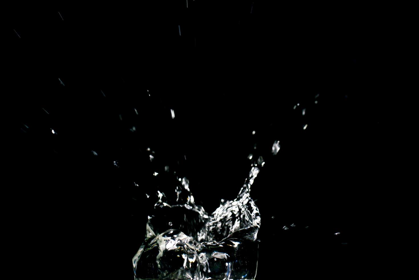 water spatten op een zwarte achtergrond. abstracte achtergrond van water verspreid op zwarte achtergrond foto