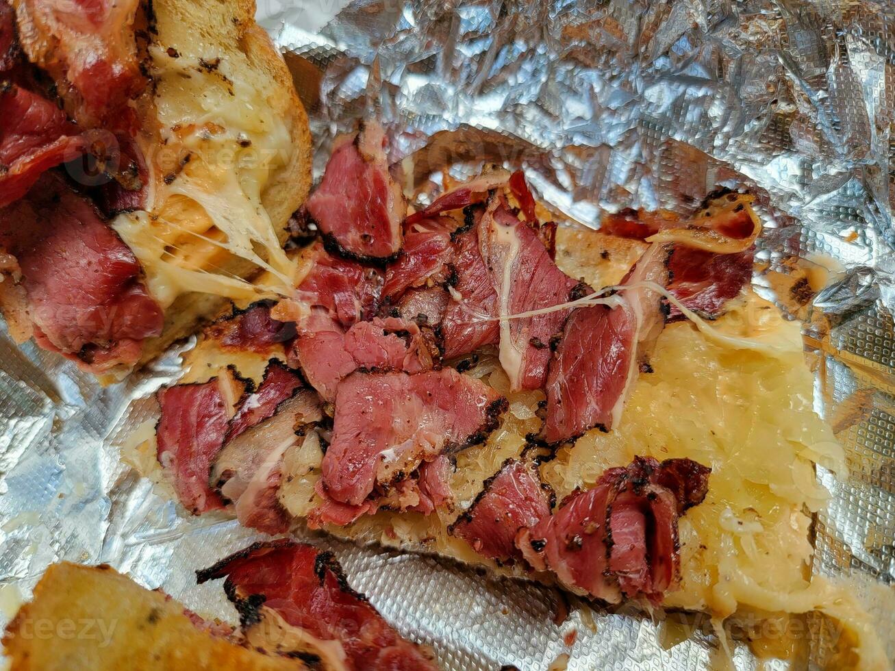 hete pastrami en zuurkool en kaassandwich op folie foto