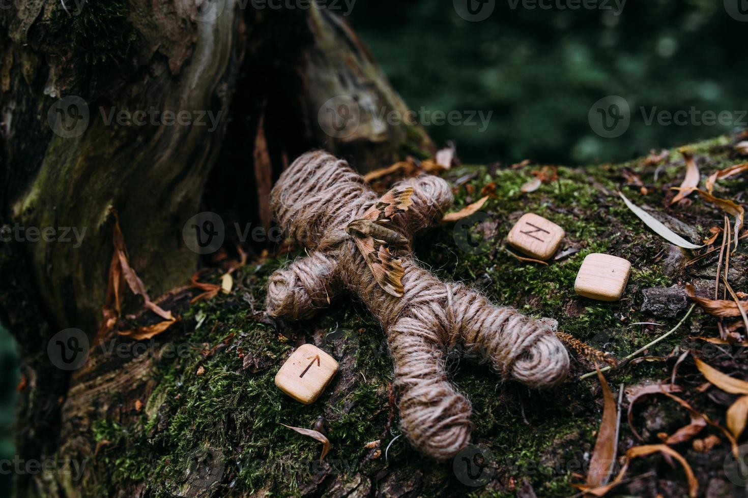 een geweven voodoo-pop van draden, mot en runen in ritueel in mysterieus bos. foto