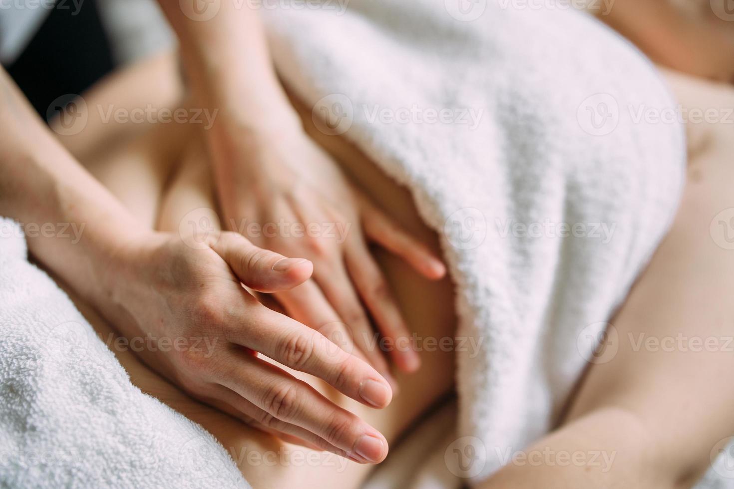 de masseur geeft een massage aan de vrouwelijke buik in de spa. het concept van cosmetische procedures. foto