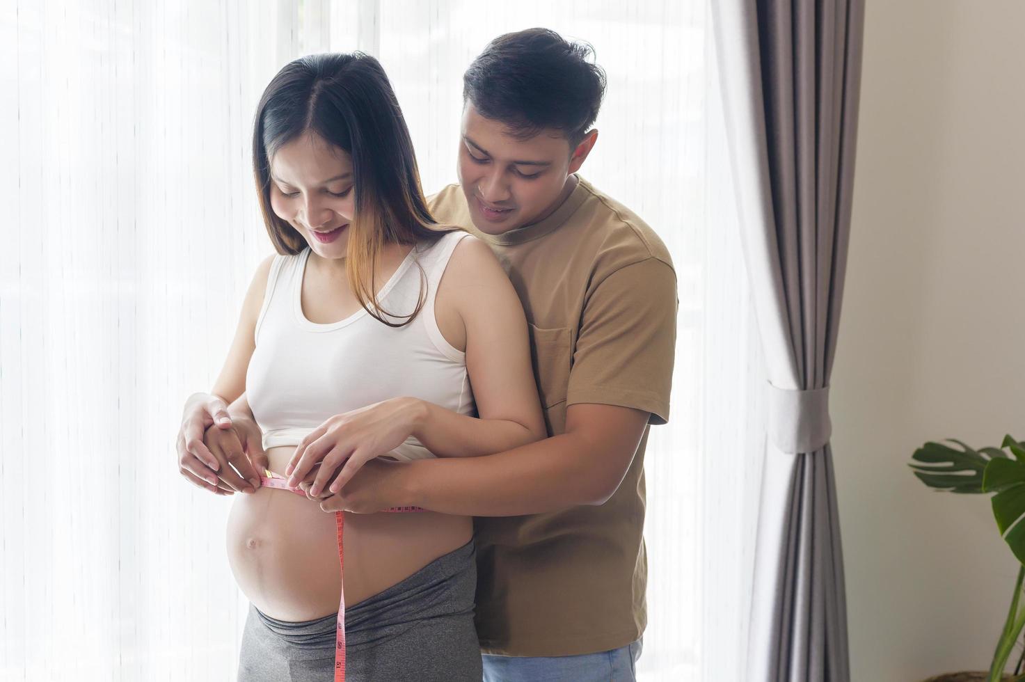 jonge zwangere vrouw die buikcentimeter meet, gezondheidszorg en zwangerschapszorg foto