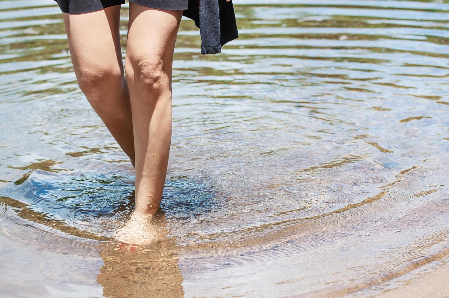 vrouw been loopt in heldere schone rivier met zandbed - mensen ontspannen vakantie slow life concept foto