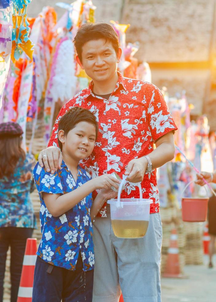 thaise familie neemt deel aan oude traditionele activiteit in een tempel tijdens songkran-festival in chiang mai, noordelijk thailand, zeer beroemde gebeurtenis van thailand foto