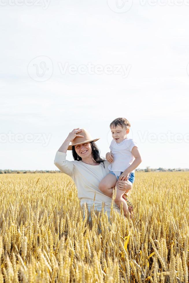 gelukkig gezin van moeder en kind dat op tarweveld loopt foto